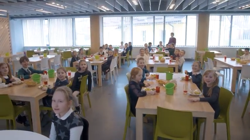 Діти за обідніми столами шкільної їдальні